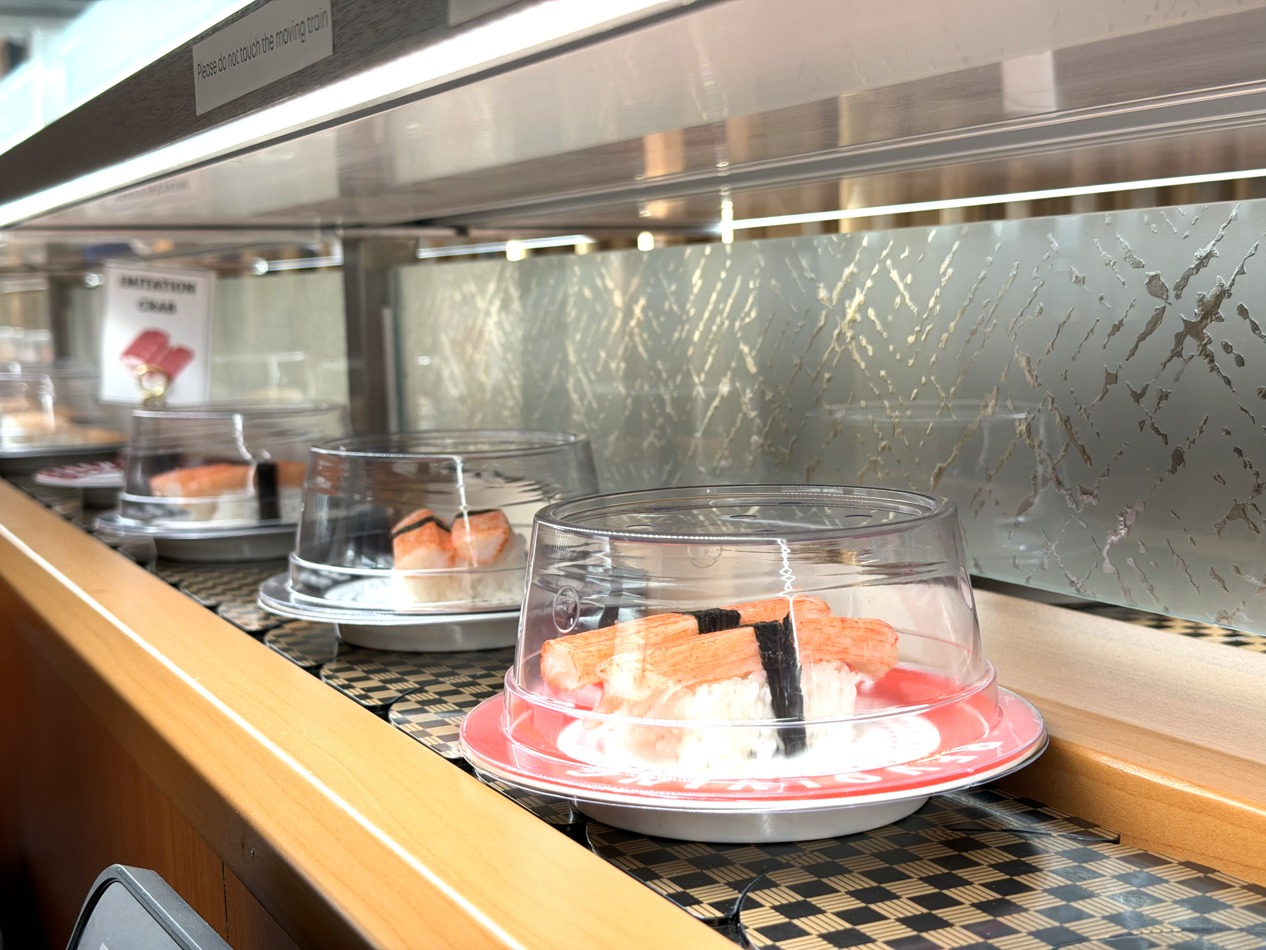 Multiple sushi plates with labeled prices on the conveyor belt at Makoto Staten Island