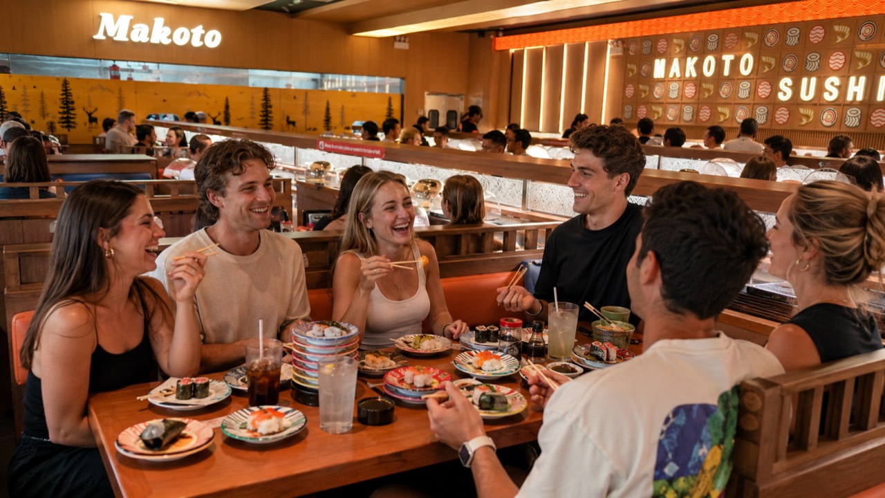 Friends gathered around the belt at Makoto Group of friends laughing and sharing plates of revolving sushi at Makoto Staten Island