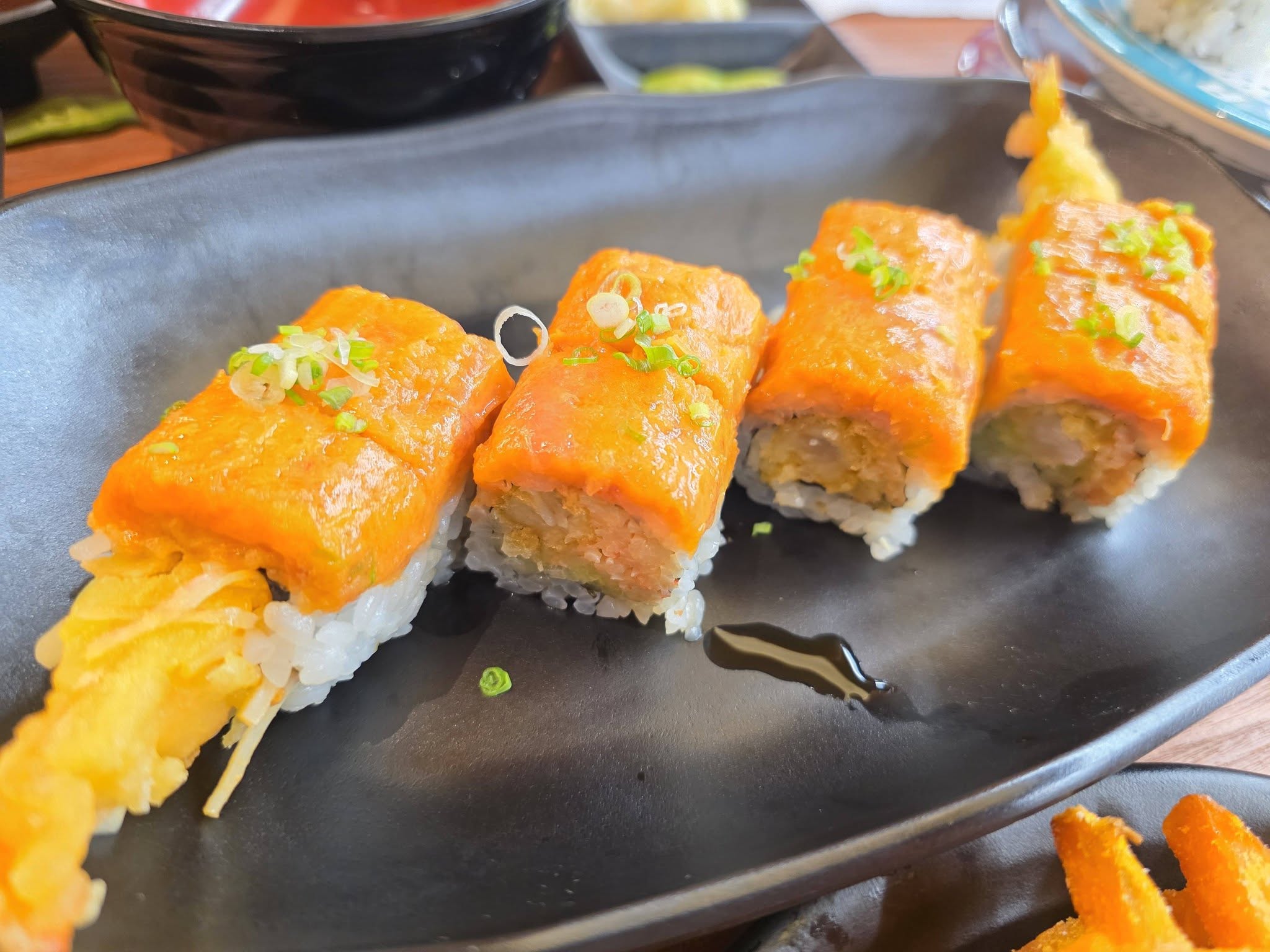 Spicy salmon and shrimp tempura roll on black plate at Makoto Staten Island
