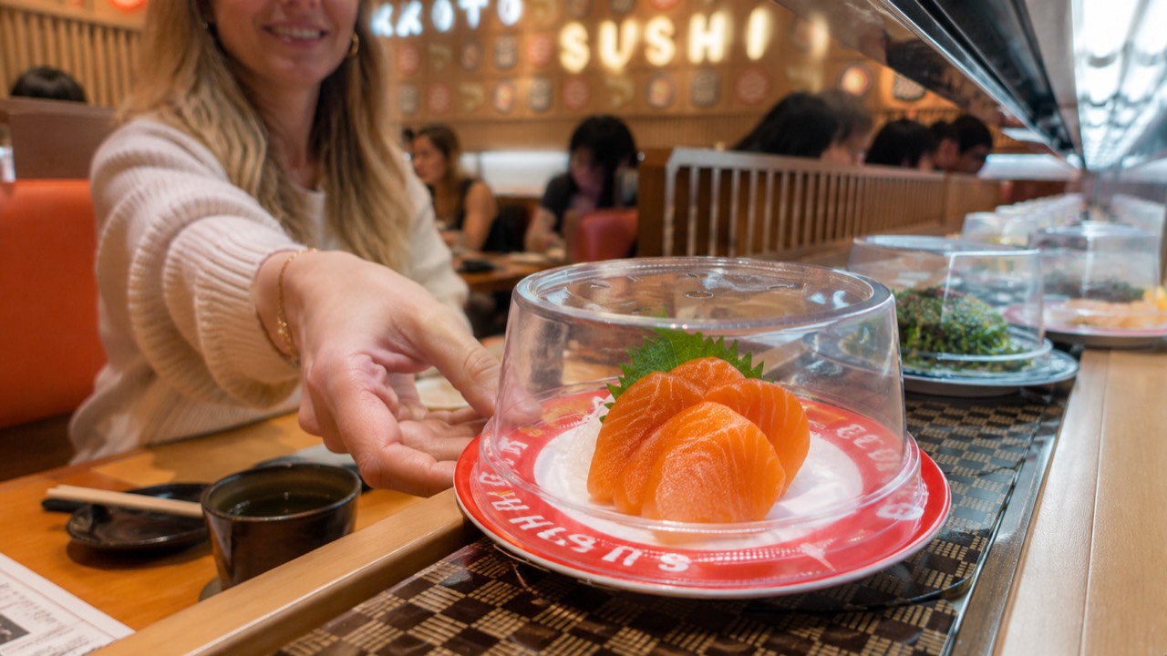 Lifting a dome to grab a plate Guest lifting the dome cover to take a salmon sashimi plate off the conveyor belt at Makoto Staten Island