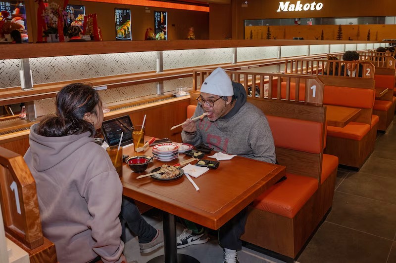 Couple dining in a booth beneath the Makoto sign in Staten Island