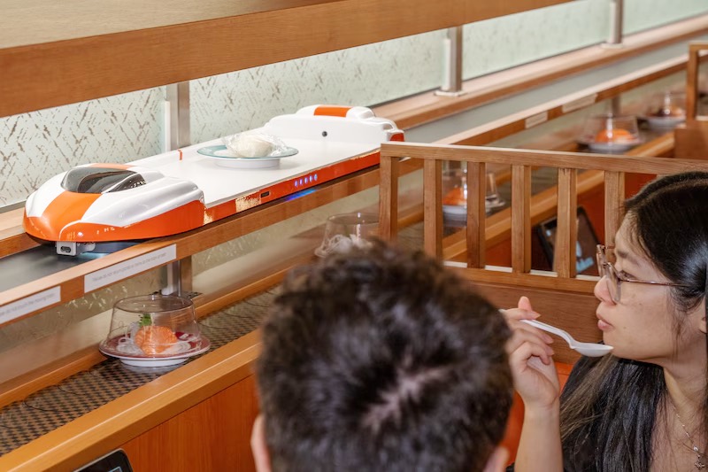 Couple watching the bullet-train express lane deliver sushi at Makoto Staten Island