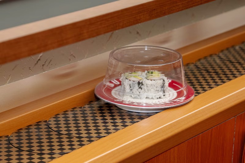 Covered plate of sushi traveling the revolving belt at Makoto Staten Island