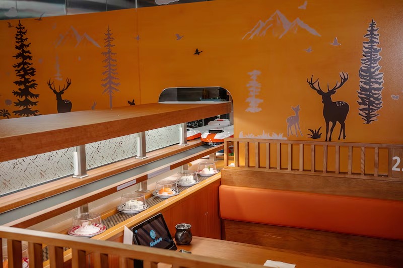 Makoto dining room with a mountain and deer wall mural above the orange booths in Staten Island