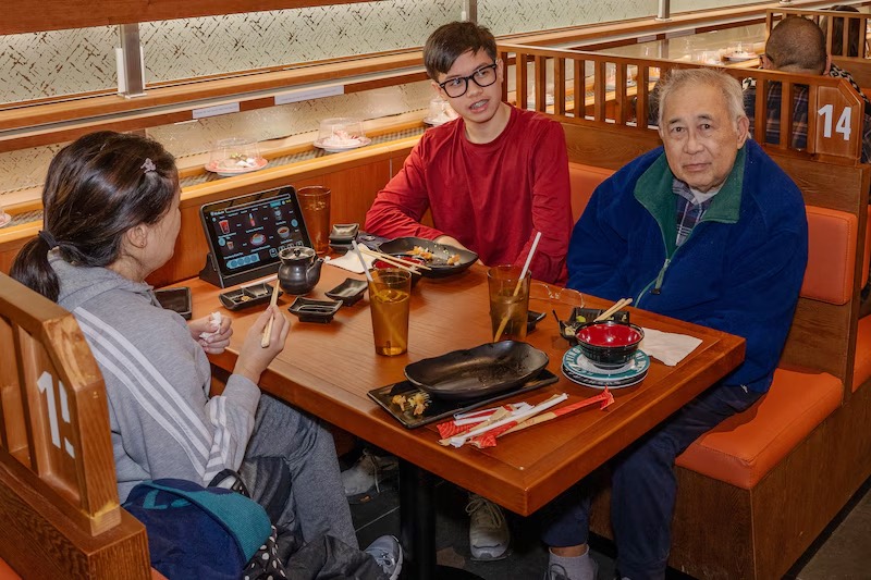 Family sharing a sushi dinner around a booth table at Makoto in Staten Island