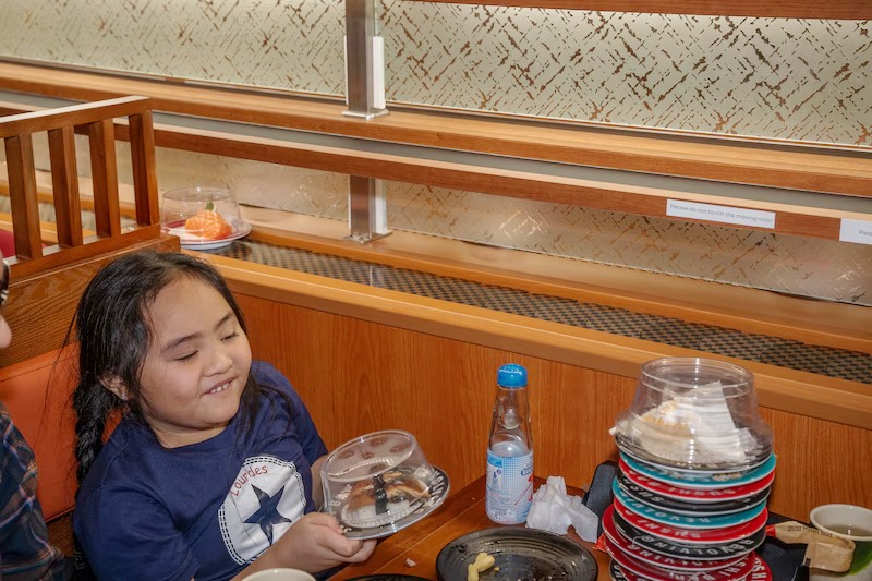 Young guest enjoying a plate of sushi in a booth at Makoto Staten Island