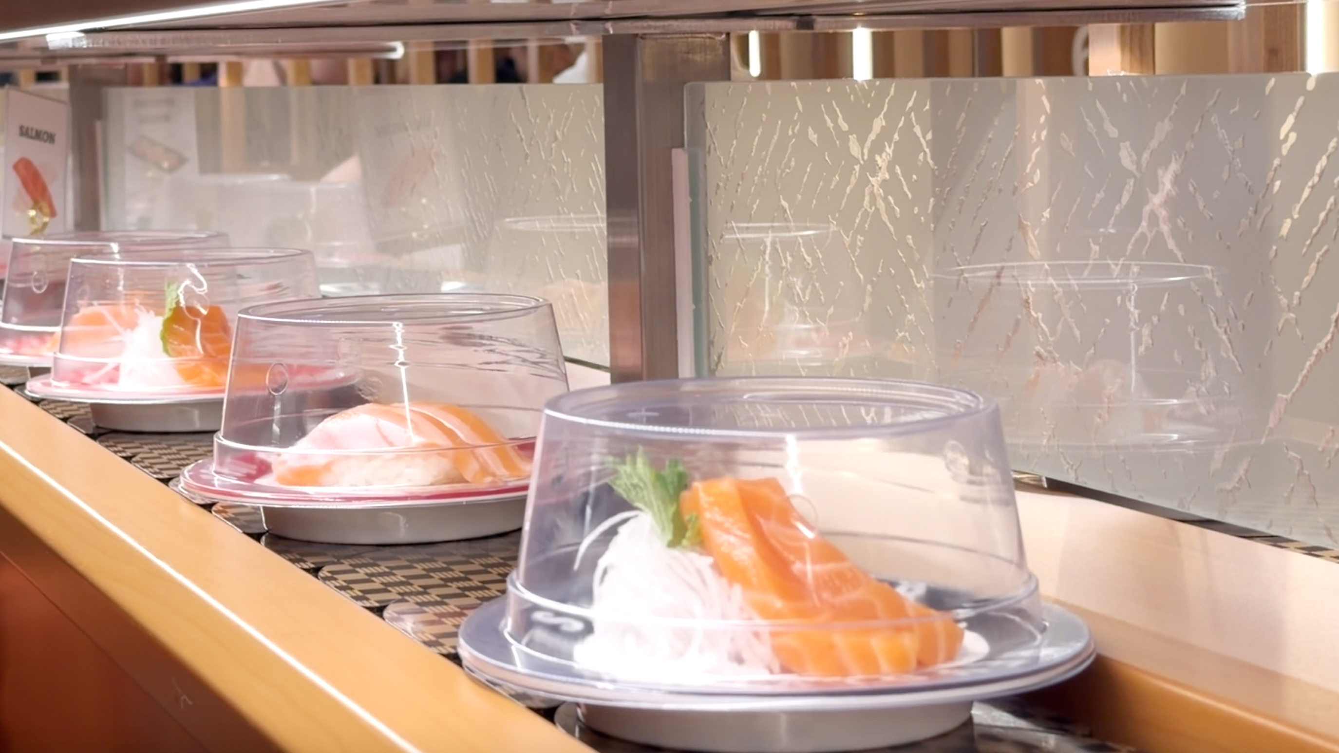 Salmon sashimi and nigiri on the belt Salmon sashimi with daikon and salmon nigiri plates on the belt at Makoto Staten Island